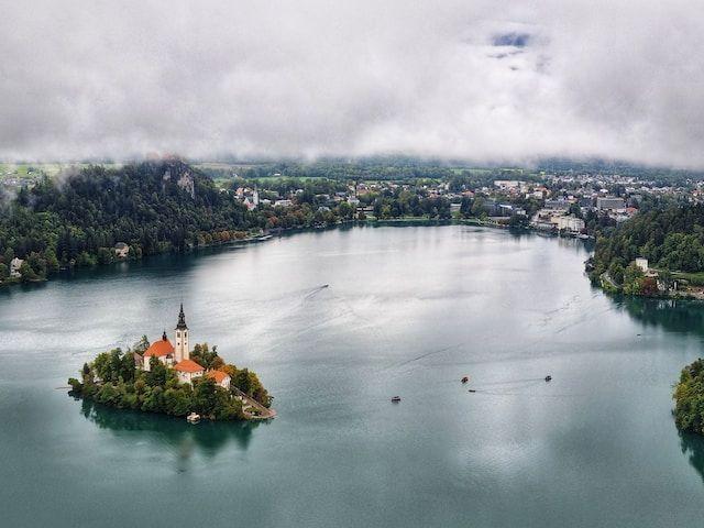 Lago con isla en el centro, iglesia y paisaje de montaña